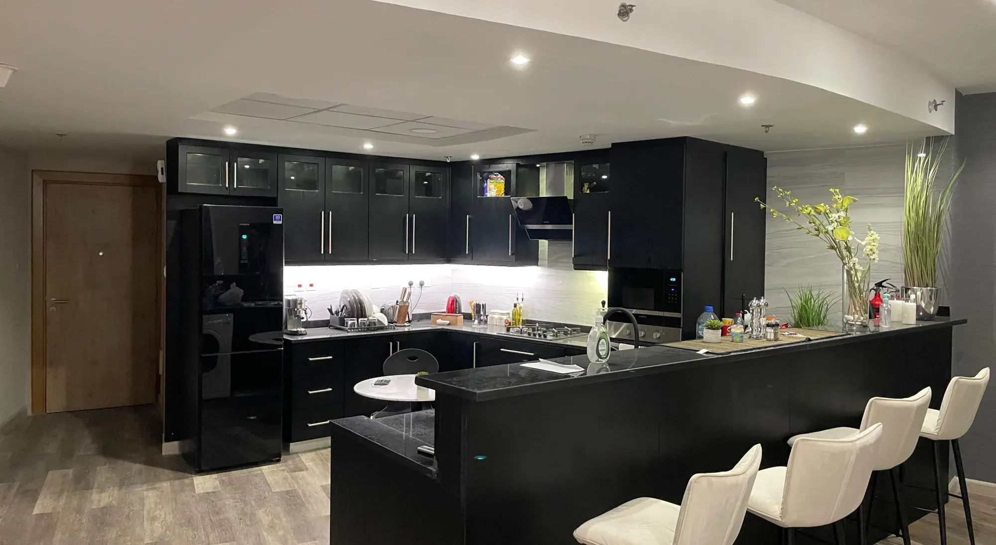 Black oak kitchen with breakfast bar and white stools