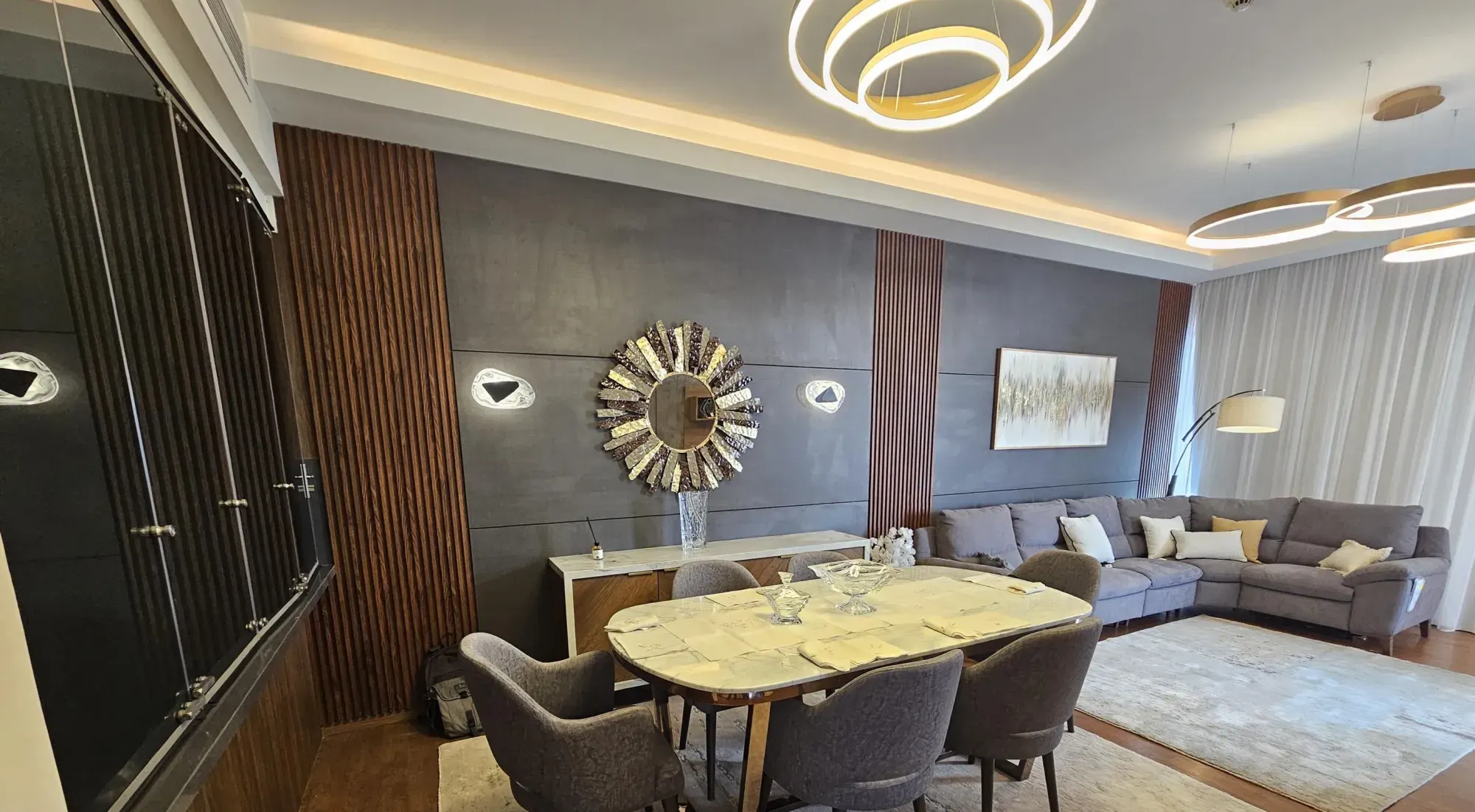 Living and dining room with walnut fluted panels and ring chandeliers